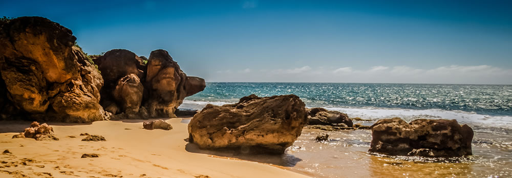 sandy beach with boulders and waves